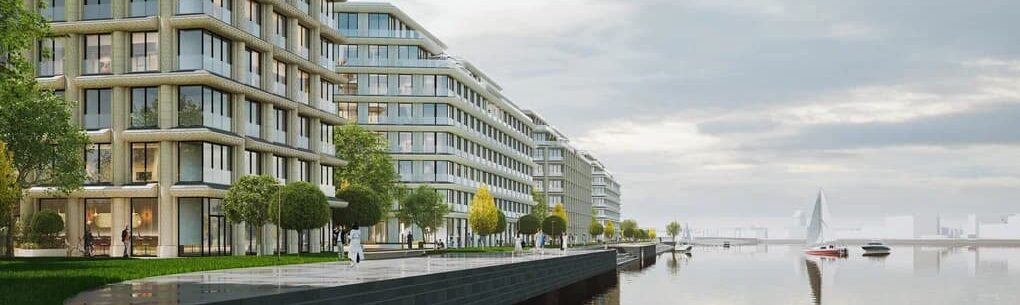 Современные жилые здания на набережной в окружении зелени с видом на воду.